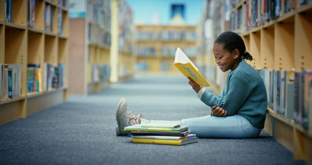 Girl, reading in the library while sitting on the floor